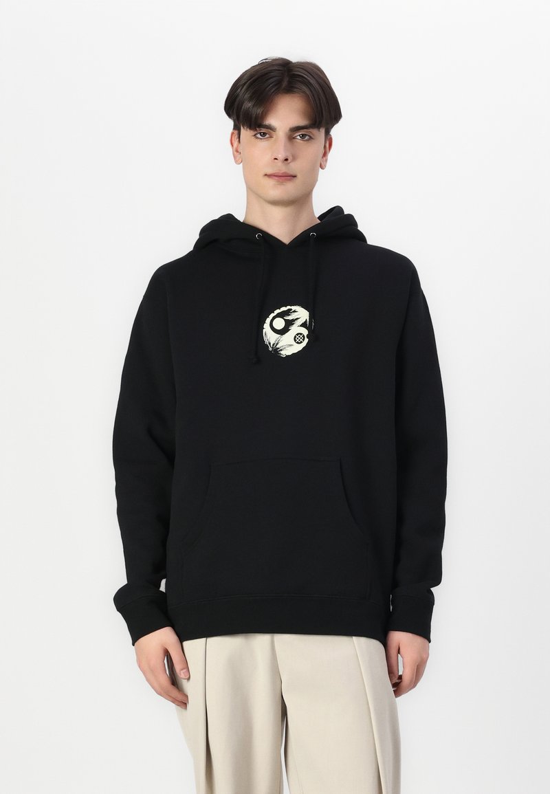 Μαύρη κουκούλα φούτερ με μπροστινή τσέπη και κρεμ έμβλημα yin-yang στο στήθος. Κατασκευασμένη από υλικό φλις με ριμπ στις μανσέτες και στη μέση.