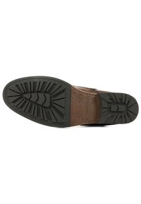 Scarpa in pelle marrone con suola in gomma scura e testurizzata, dotata di un battistrada lavorato per una migliore aderenza; cuciture visibili lungo il bordo.