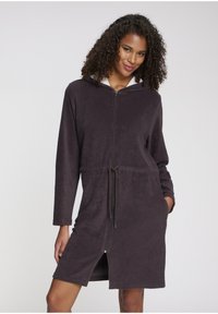 Temno sivo flis haljo z zadrgo, dolgimi rokavi, kapuco in elastičnim pasom. Ima stranske žepke in dolžino do sredine stegna.