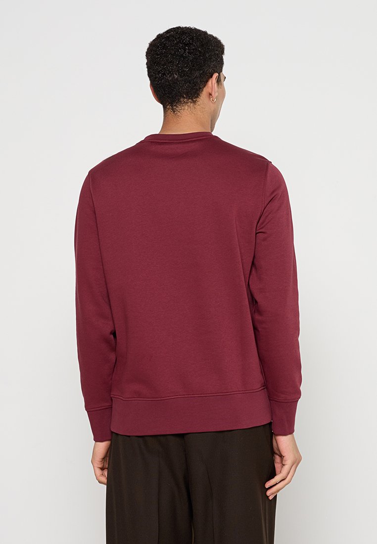 Sudadera burdeos de manga larga, con cuello redondo y puños de canalé. Textura de tela suave, con un color sólido sin estampados.