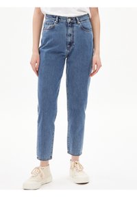 Jeans de denim azul con una cintura alta, ajuste recto y un ligero desvanecimiento. Cuenta con cinco bolsillos y cierre de botones.