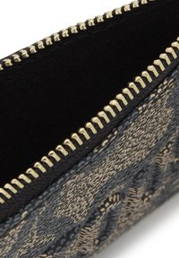 Black and gold zipper pouch with textured woven pattern in shades of beige and blue; soft inner lining visible along the opening.