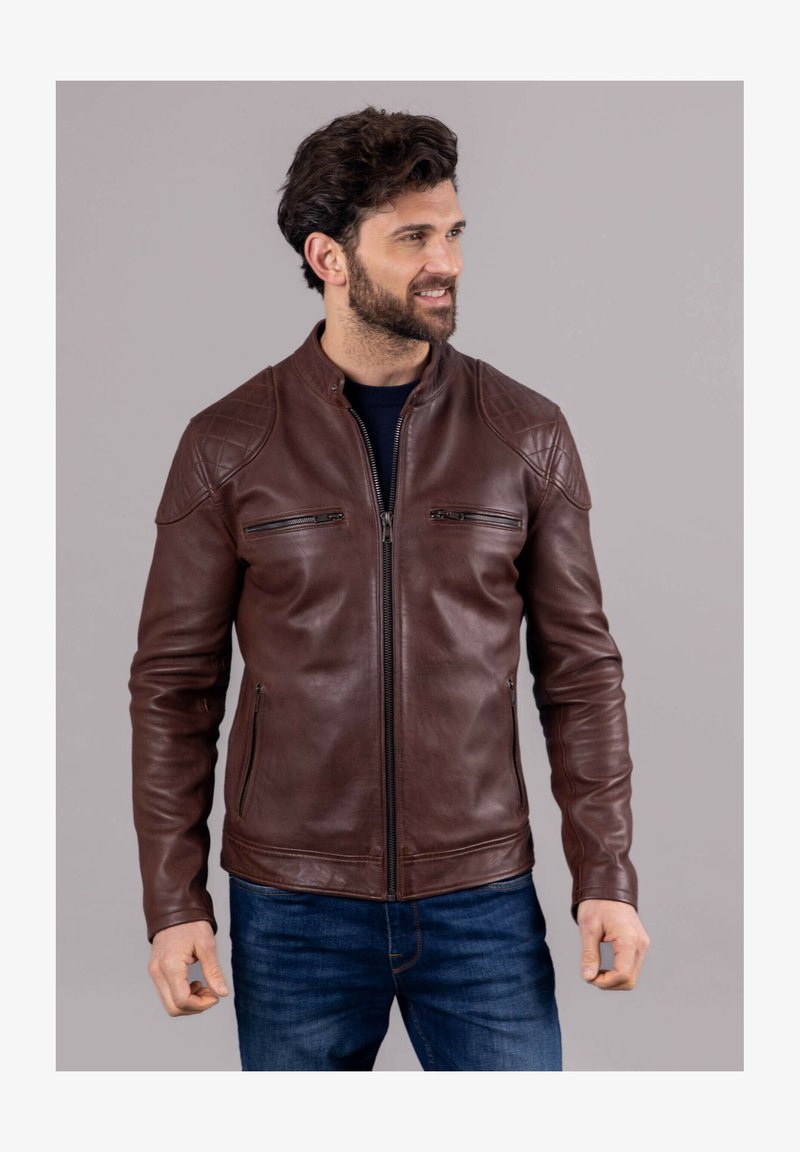 Brown leather jacket with quilted shoulder accents, zippered chest pockets, and a stand collar. Soft texture with a fitted design.