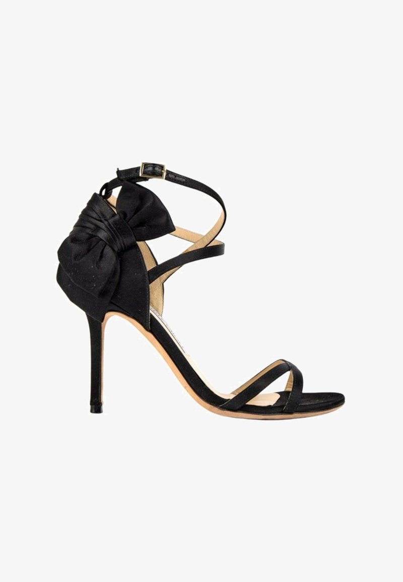 Sandale noire à talon haut avec bride à la cheville, fine bride à l’orteil et grand nœud en tissu à l’arrière du talon.
