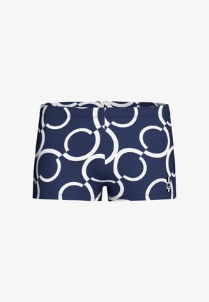 Tmavě modré plavky s bílými překrývajícími se kruhovými vzory a malou černo-bílou značkou v pravé dolní části.