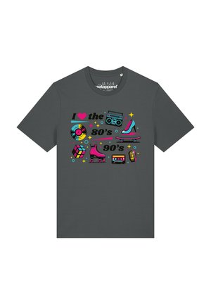 T-shirt gris foncé avec des icônes colorées des années 80 et 90, comprenant un disque vinyle, un boombox, un talon haut, un skateboard, un Rubik’s cube, des patins à roulettes, une cassette et un microphone.