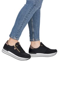 Black athletic shoes with a textured upper, leopard print accents at the heel, gold zip detail, and white striped sole.