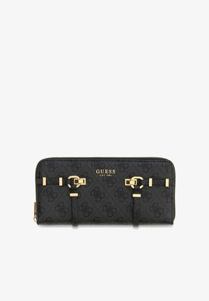 Schwarze Guess Reißverschlusstasche mit goldenen Schnallen, Logoprint-Muster und goldener Aufschrift "GUESS EST 1981" auf der Vorderseite.