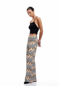 Cropped top nero a coste con spalline sottili abbinato a pantaloni a vita alta svasati con un motivo a zigzag in nero, bianco e arancione.