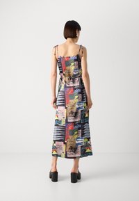 Abito lungo con stampa grafica colorata, spalline sottili e vestibilità ampia. Il materiale sembra leggero con una texture liscia.