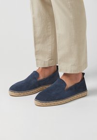 Espadrilles de ante azul marino con puntera redonda y lados abiertos, que cuentan con una suela de yute natural y un ribete cosido.