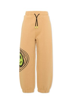 Pantaloni della tuta beige con elastico in vita e polsini, cordino nero con punte gialle, e una grande grafica parziale di una faccina sorridente verde sul lato.