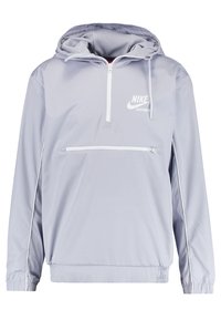Light gray Nike windbreaker with a half-zip front, adjustable hood, front pocket, and white accents along the sleeves and hem.