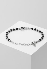 La pulsera de cuentas negras y cadena plateada presenta cuentas de color negro mate y cuentas plateadas brillantes en alternancia, con un cierre de ancla y un pequeño acento de etiqueta.