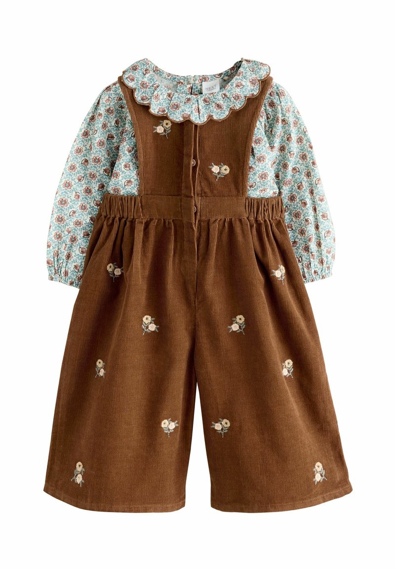 Bruine corduroy jumpsuit met een lichtblauw bloemdecor blouse, gekruiste kraag, en geborduurde bloemen op de voorkant en de benen.