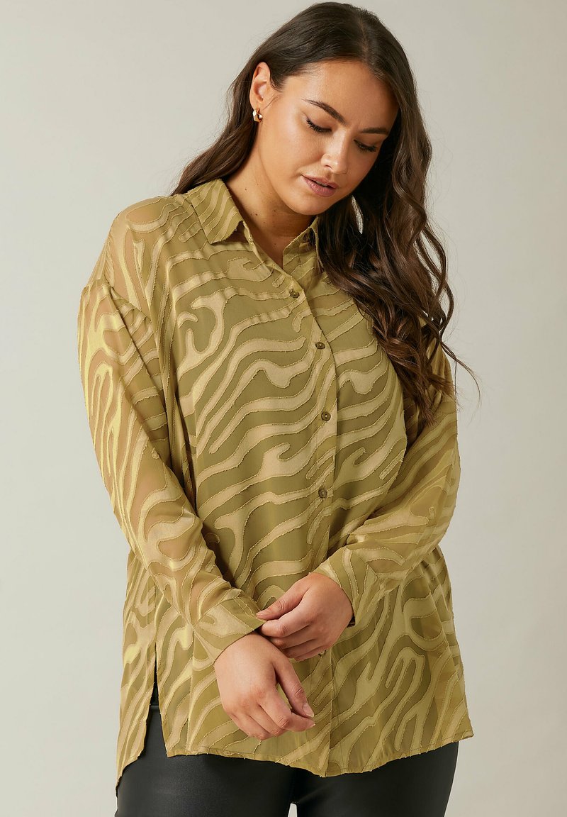 Sheer blouse in olive green with a wavy pattern, featuring a button-down front, long sleeves, and side slits at the hem.