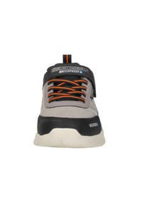 Zapatillas impermeables en gris y negro con cordones naranja, que presentan una parte superior texturizada, suela gruesa y una marca prominente en la lengüeta.