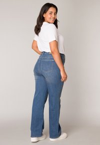 Hoge taille blauwe spijkerbroek van denim, met een recht design, subtiele wassing en achterzakken, gecombineerd met een wit shirt.