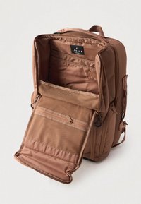 Brown Jordan hátizsák, teljesen nyitott fő rekesszel, amelyben párnázott laptop zseb és cipzáras hálós zseb található az első fedélen.