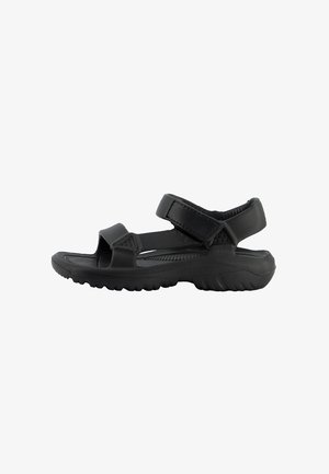 Sort åben sandal med to justerbare remme og en tyk tekstureret sål, designet til udendørs eller afslappet brug.