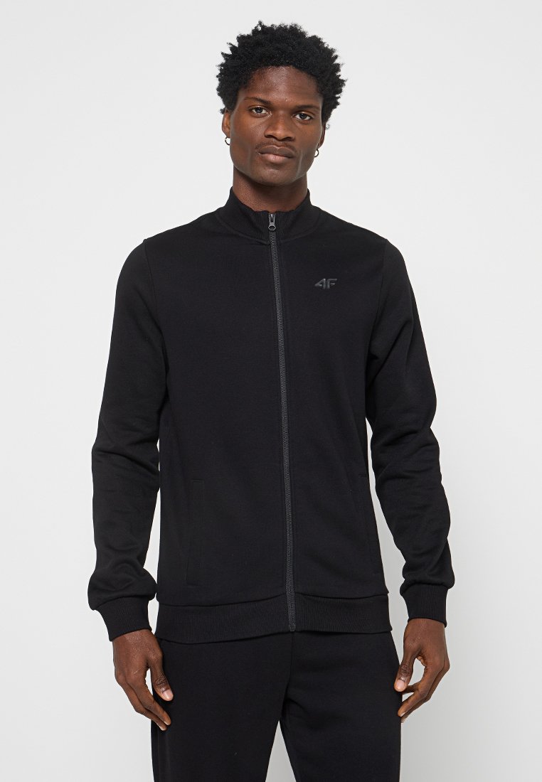 Chaqueta negra de cremallera con un cuello alto, hecha de una tela suave, con bolsillos laterales y un logo sutil en el pecho.