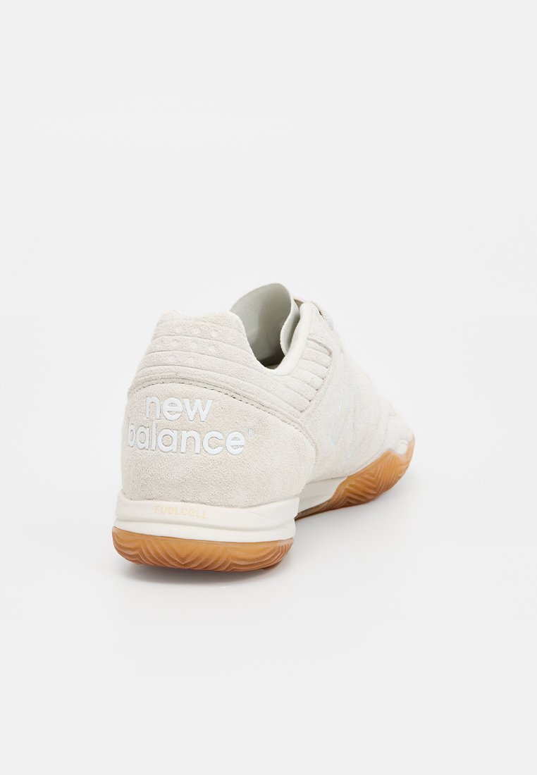 Lichtgrijze suède schoen met een gestructureerde afwerking, met witte "new balance" branding, een gevoerde zool en een gumrubberen buitenzool.
