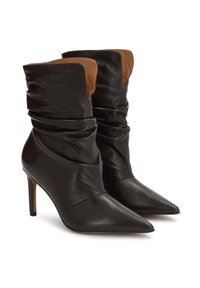 Melnas ādas zema potīte uzslāņotas zābaki ar norādītiem pirkstiem un stiletto papēžiem, kuru augšdaļā redzama brūna iekšējā odere.