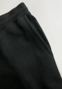 Schwarze Baumwoll-Sweatpants mit strukturierter Oberfläche und einer Seitentasche. Der Bund ist elastisch für zusätzlichen Komfort.