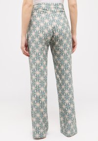 Weit ausgestellte Hosen in einem grünen, beigen und cremefarbenen geometrischen Muster, mit hoher Taille und glattem, leichtem Stoff.