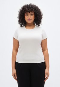 Λευκό κοντομάνικο μπλουζάκι με στρογγυλή λαιμόκοψη, κατασκευασμένο από ριμπ ύφασμα. Η γραμμή είναι casual και η υφή φαίνεται απαλή και λεία.