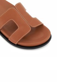 Brown leather slide sandal with a pronounced rectangular cutout design. Features contrasting white stitching and a smooth black sole.