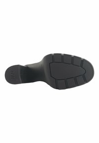 Suela de zapato de goma negra con una superficie texturizada, que presenta estrías horizontales y verticales para tracción y estabilidad.