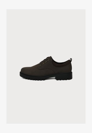 Chaussure en cuir marron foncé à lacets avec semelle noire épaisse et languette derrière le talon, vue de profil sur un fond clair uni.