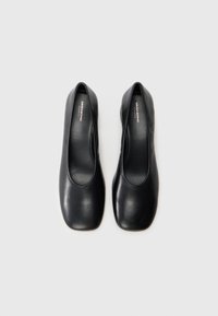 Black leather ballet flats with a rounded toe, smooth texture, and minimalistic design. Interior features a soft lining for comfort.