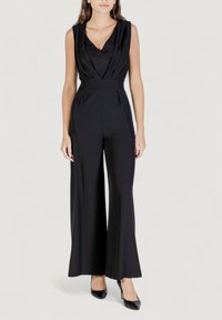 Mono negro con escote en V profundo y plisado, diseño sin mangas y pantalones de pierna ancha. Confeccionado en una tela suave con cintura ajustada.