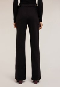 Zwarte op maat gemaakte broek van gladde stof, met een hoge taille, twee goudkleurige hardwareaccenten en een recht gesneden ontwerp.