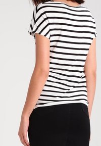 Sort og hvid stribet kortærmet t-shirt med rund halsudskæring, der har en afslappet pasform og blødt, let stof.