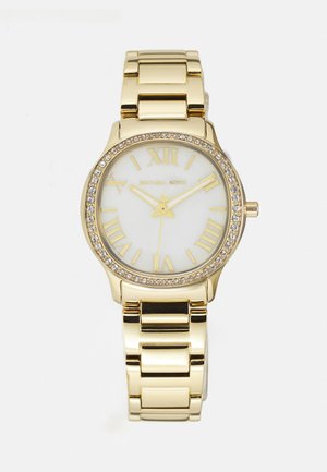 Goldfarbene Uhr mit rundem Gehäuse, weißem Zifferblatt, römischen Ziffern und einem mit Kristallen besetzten Lünette. Verfügt über ein Gliederarmband mit glänzender Oberfläche.