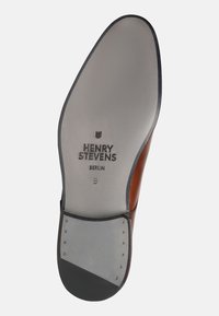 Suola in pelle marrone con dettagli cuciti, testo del logo "HENRY STEVENS BERLIN", suola in gomma grigia, forma arrotondata, texture liscia.