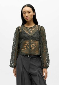 Sheer, dark green lace blouse with intricate floral patterns, featuring long puffed sleeves and a round neckline, button front closure.