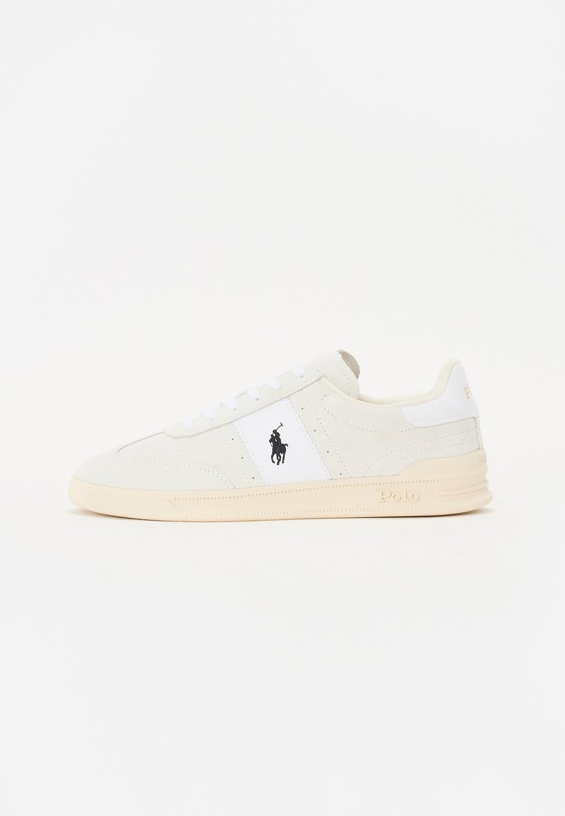 White suede sneakers with logo, featuring white textile accents, round toe, and light rubber sole. Laces are white, and heel shows "Polo."