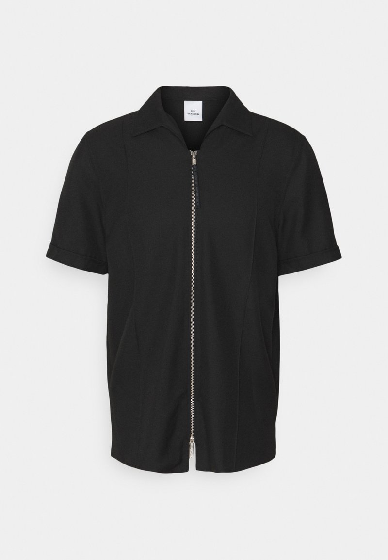Chemise noire à manches courtes avec fermeture éclair argentée à l'avant et col, en tissu lisse, présentée sur un fond clair uni.