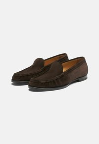 Brązowe zamszowe loafersy z zaokrąglonym czubkiem i przeszyciami; zawierają czarną płaską podeszwę oraz gładką wewnętrzną wyściółkę.