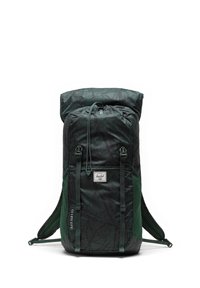 Sac à dos à carreaux verts et noirs avec un design à roulotter, cordon de serrage ajustable et bretelles rembourrées. Comprend un logo et des dimensions imprimées sur le côté.