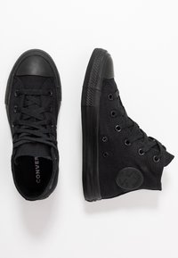 Sorte høyhælte kanvassneakers med gummitåhette, runde lisser og sirkulært logo-merke. Teksturert stoffoverlegg og glatt gummisåle.