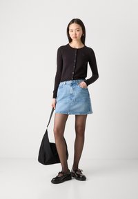 Črn jopič, svetlo modra denim krila, črna torba, črne čevlje z detajlom v obliki pentlje, in prozorne nogavice. Preprost, sproščen videz.