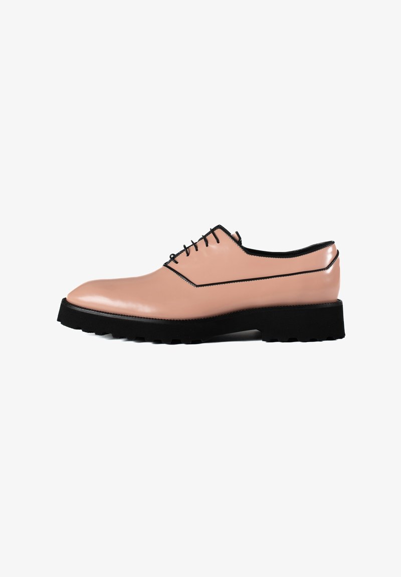 Lichtroze leren schoen met zwarte accenten, afgeronde neus en minimalistische veters. Beschikt over een dikke zwarte rubberen zool met groeven.