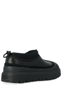 Scarpa da ginnastica nera senza lacci con tomaia testurizzata, polsino elastico e suola spessa in gomma con un motivo del battistrada pronunciato. Logo UGG sul tallone.