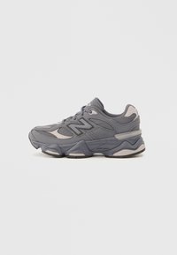 Gray athletic shoe with mixed-texture upper, featuring mesh and synthetic materials. Dual-tone design with patterned accents and a chunky sole.