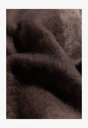 Dunkelbrauner, weicher Wollstoff mit einer feinen, flauschigen Textur, die sanfte Falten und Wellen zeigt, mit Licht, das von der Oberfläche reflektiert wird.